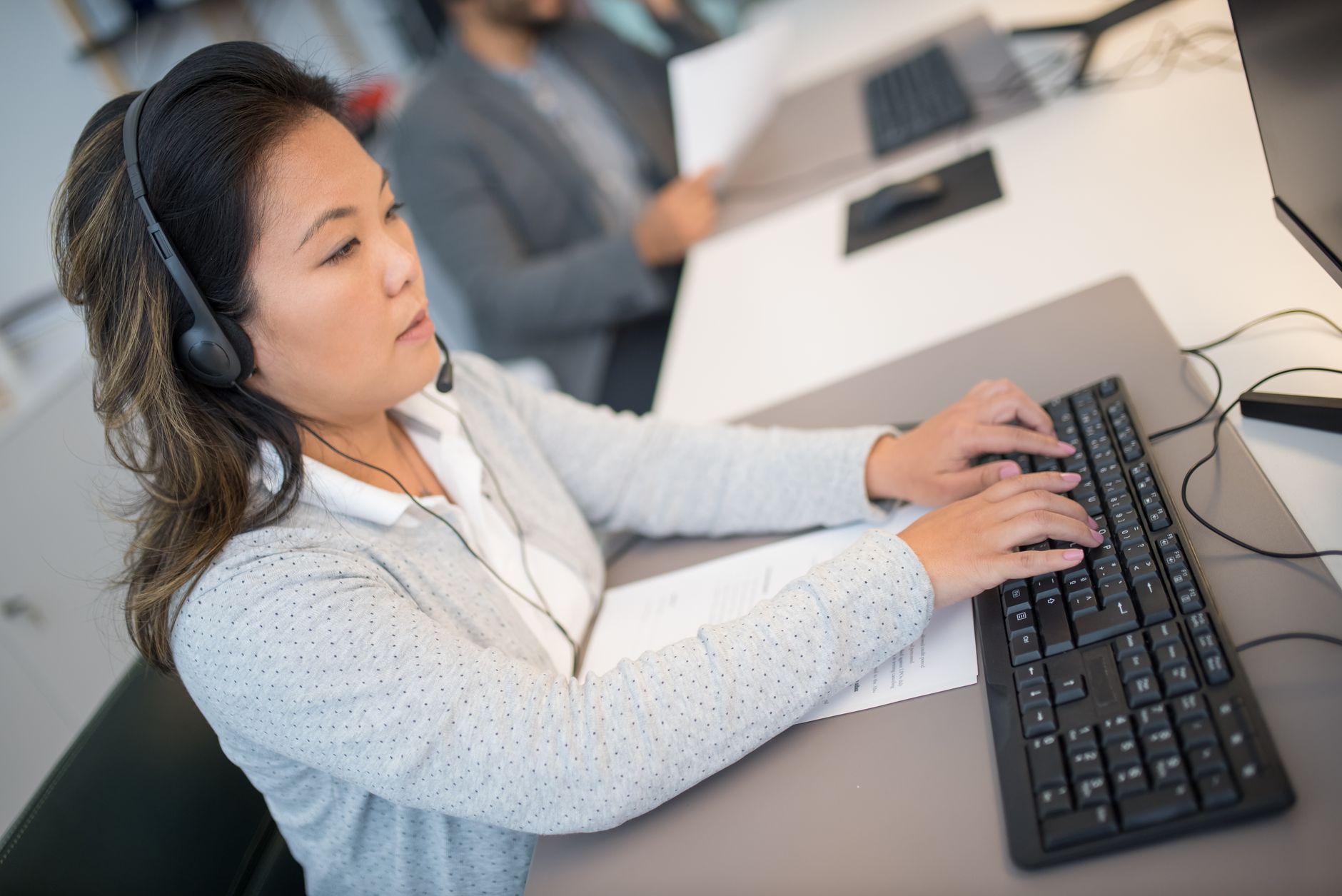 A person typing with headphones on at a desk
