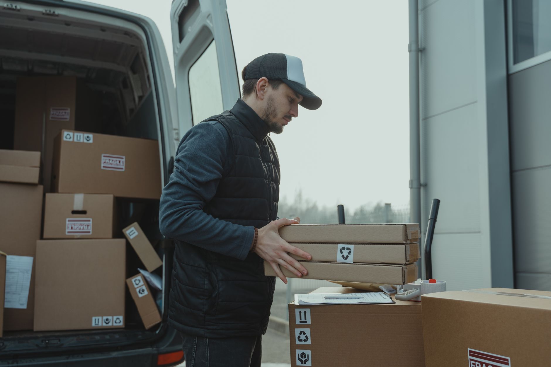 A delivery driver carrying packages beside a car