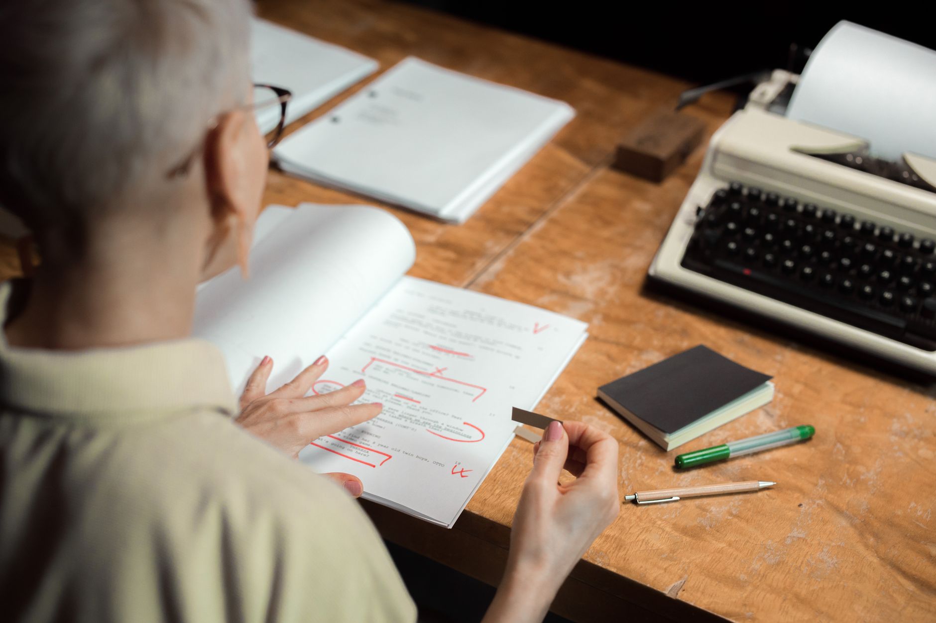 A woman editing printed pages with a red pen