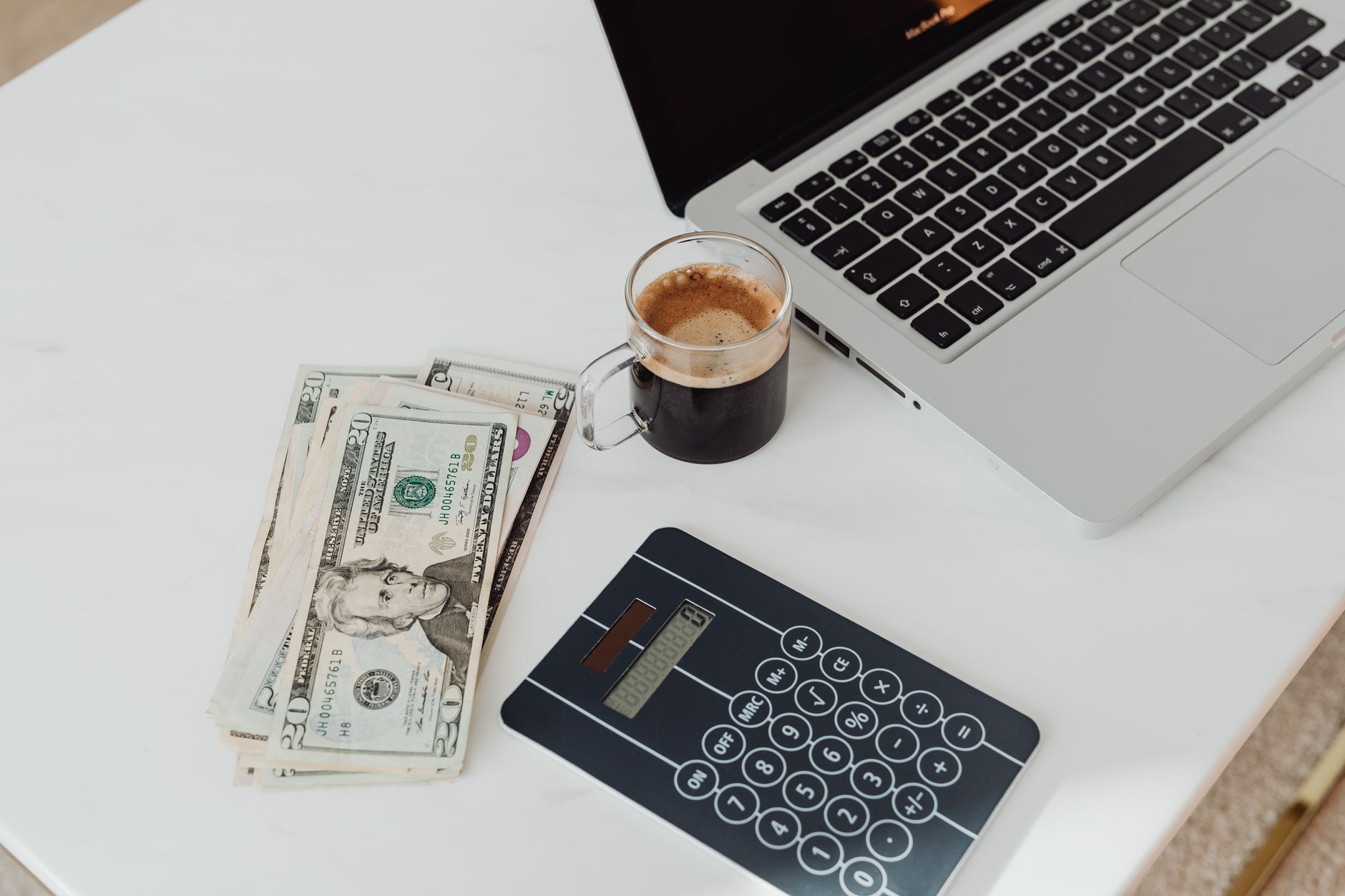 Cash and a calculator next to a laptop