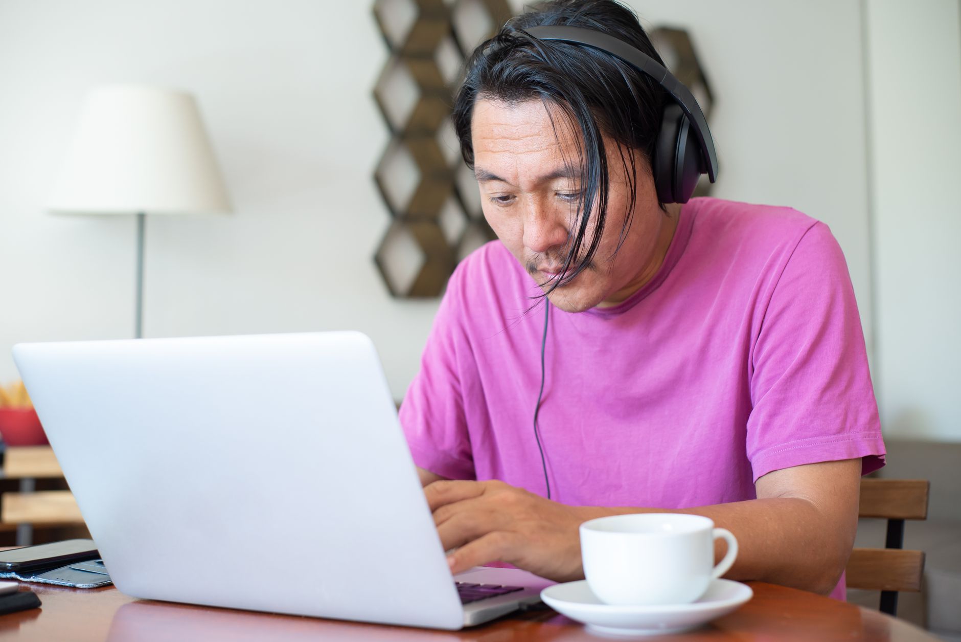 A person wearing headphones typing on a laptop