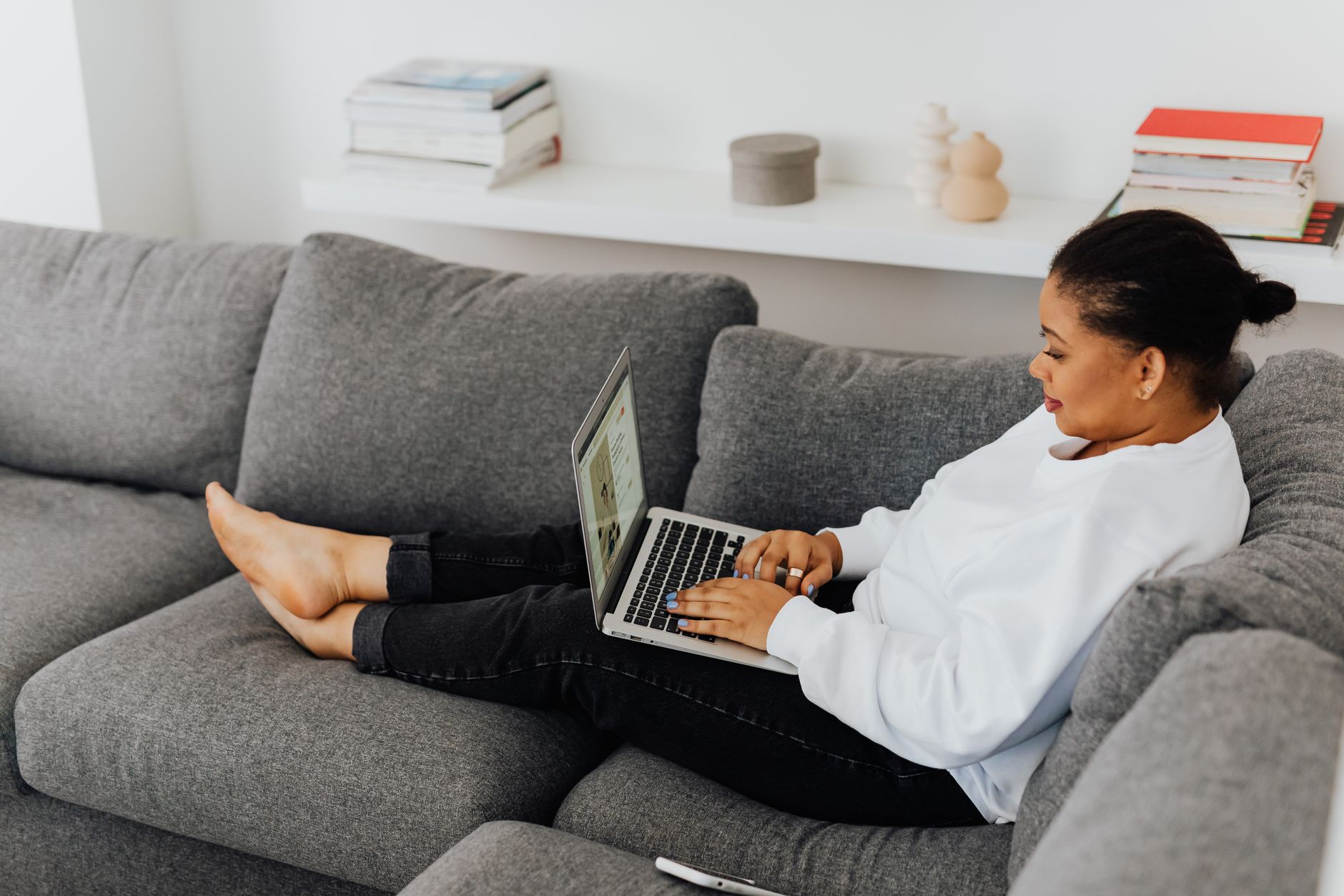 A woman working from her couch on a laptop
