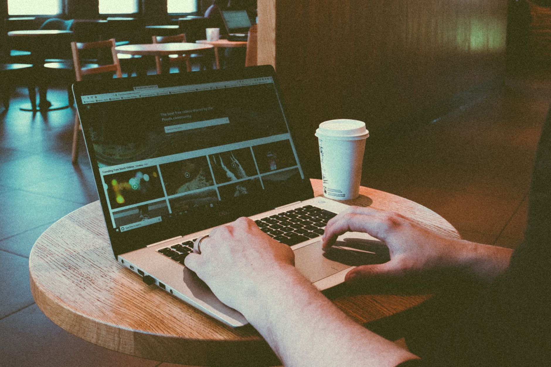 A person typing on a laptop at a cafe table