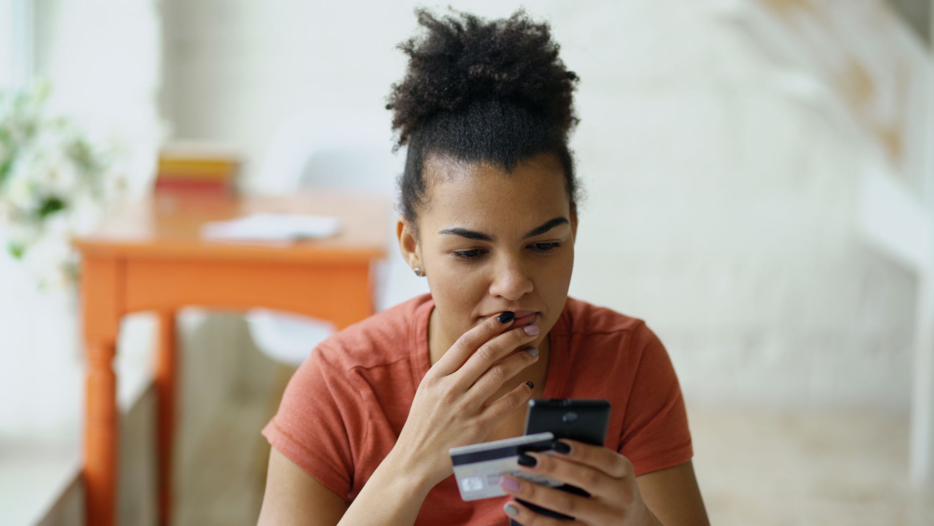 A woman shopping online with her phone and a card