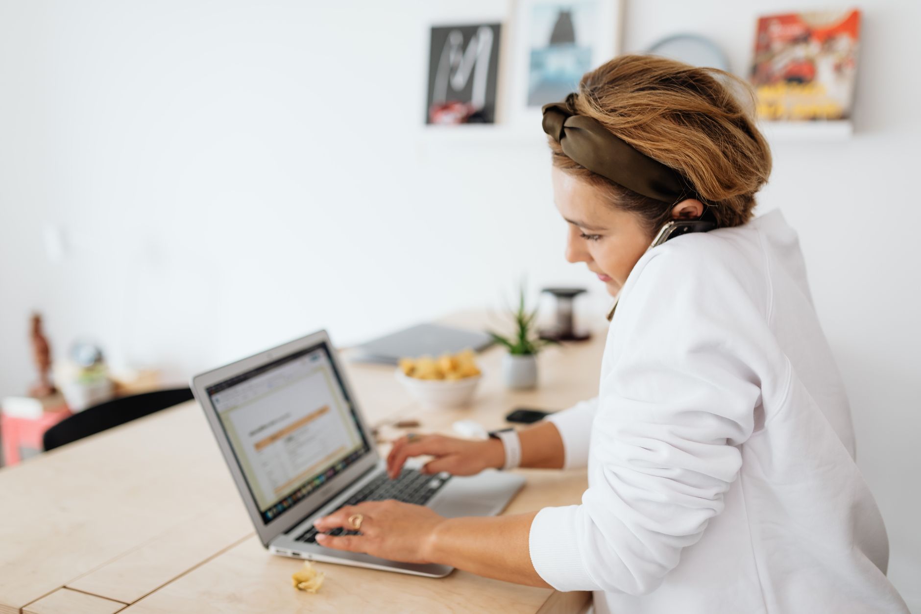 A woman with a headset working on a laptop at a home desk