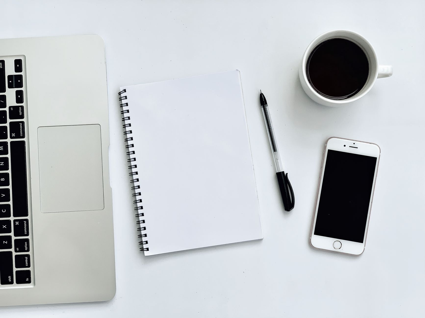 A tidy home office desk with a laptop, notebook and phone