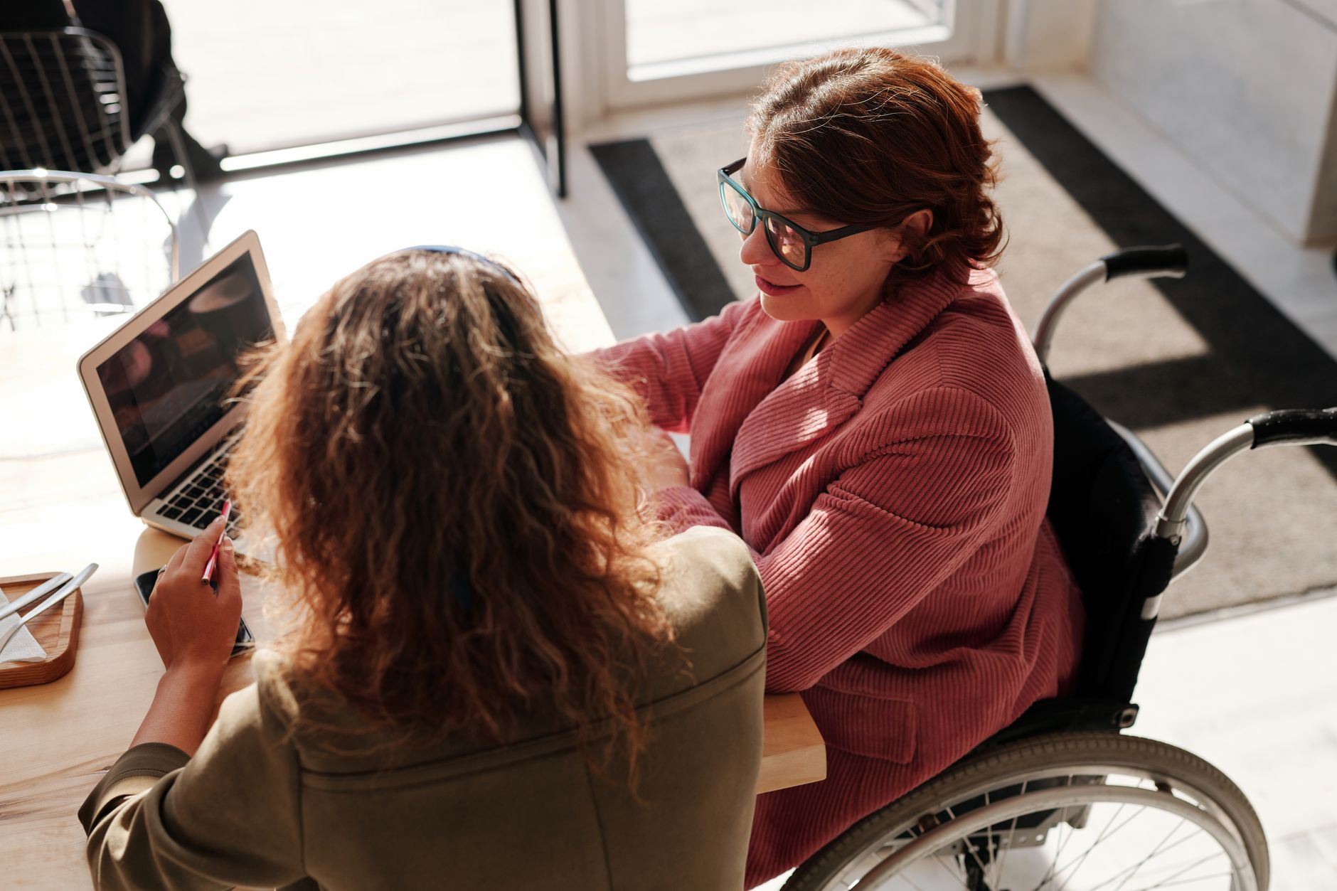 Two women collaborating on a laptop at a cafe