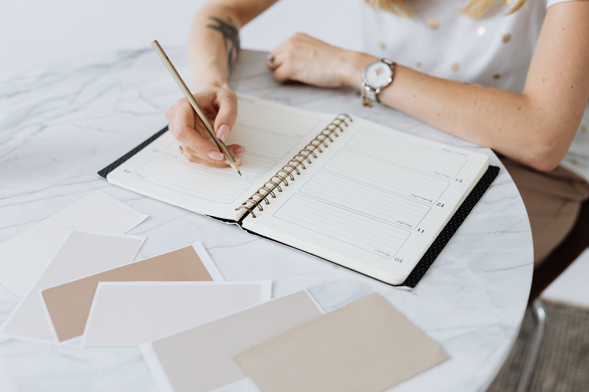A woman writing in a planner at her desk