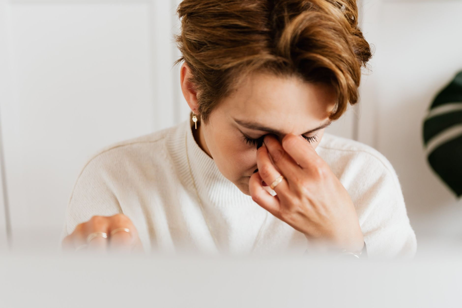 A tired woman rubbing her eyes at her laptop