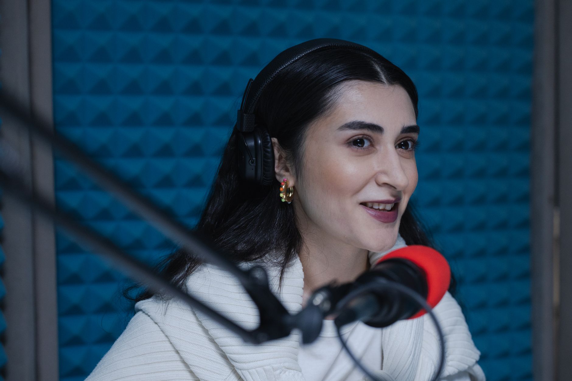 A woman speaking into a studio microphone wearing headphones