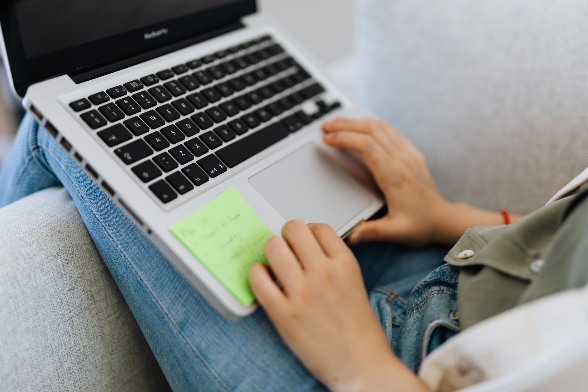 A person working on a laptop with notes beside it