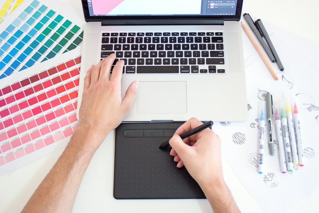 A person using a drawing tablet and laptop with color swatches