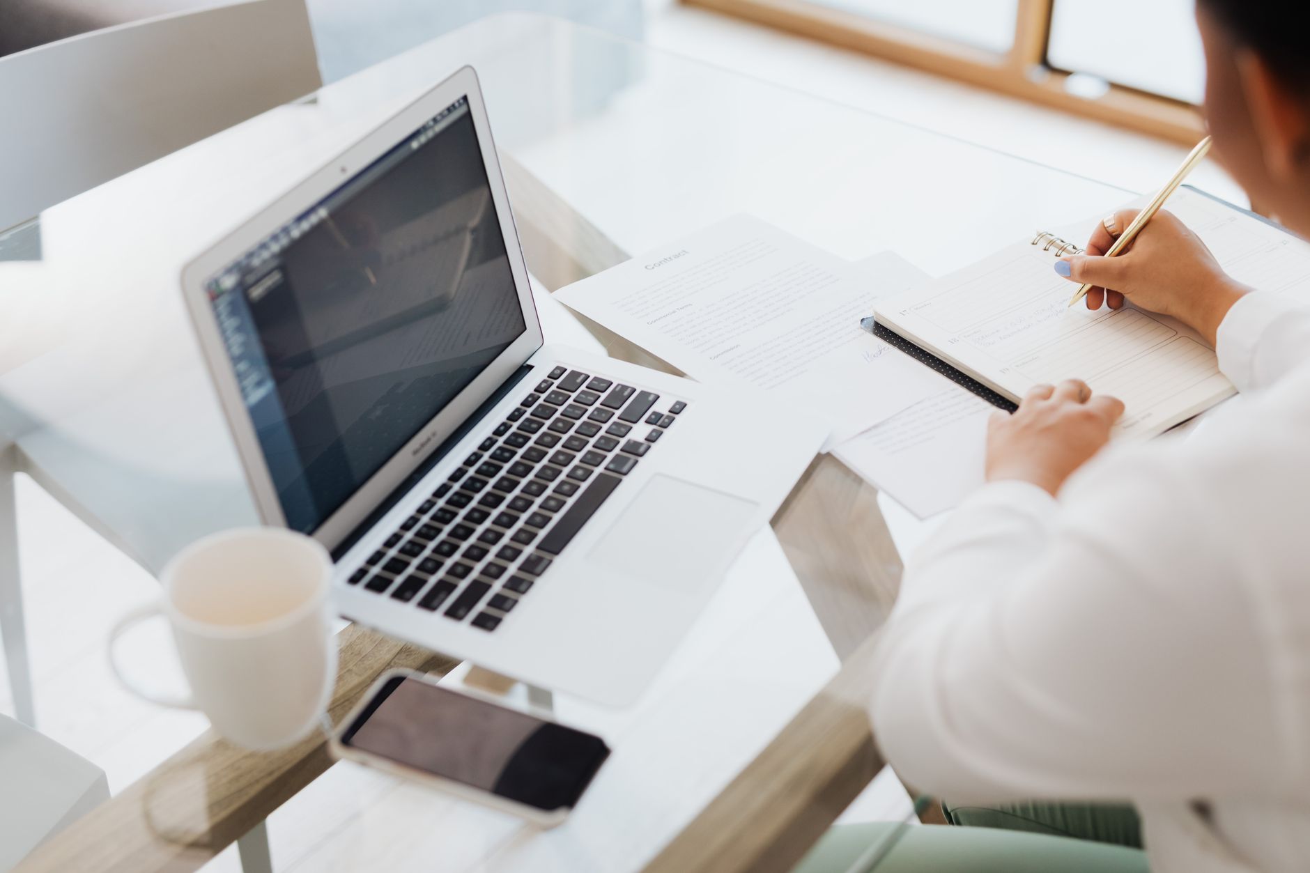 A person planning in a notebook beside a laptop