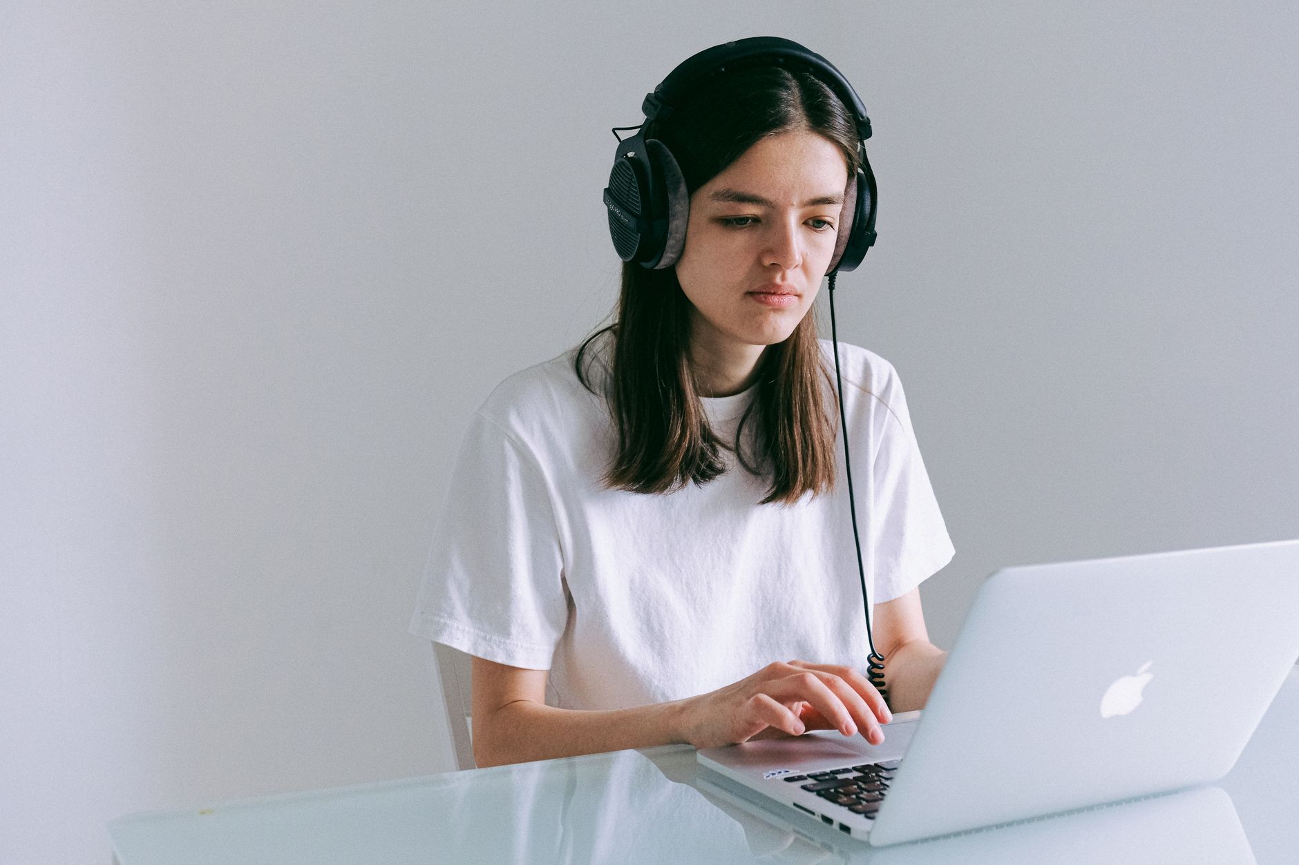 A woman wearing headphones typing on a laptop