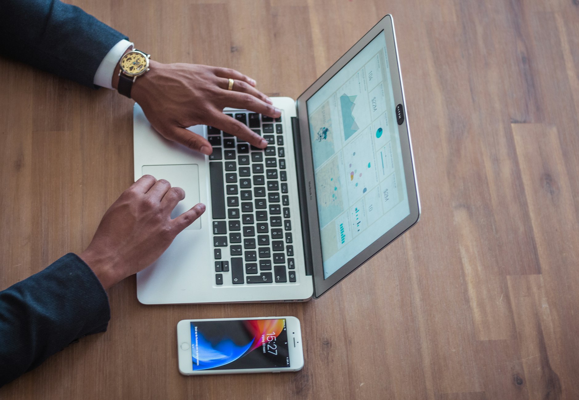 A person checking a website on a laptop and a phone side by side
