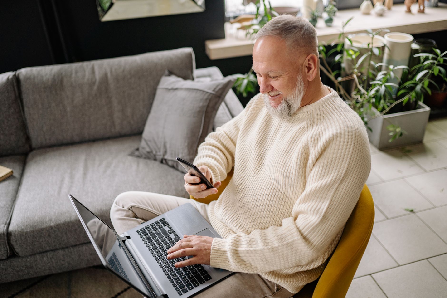 A man using a phone and a laptop at home
