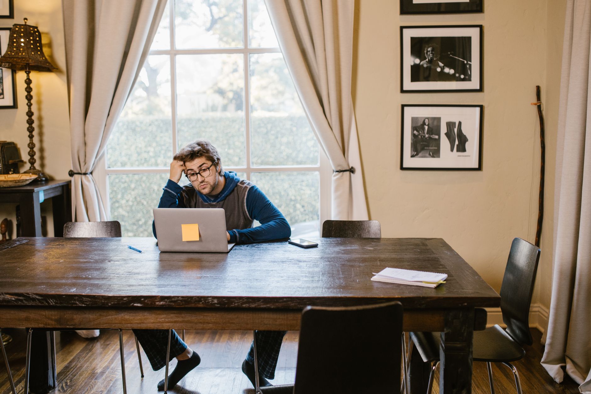 A man working alone on a laptop at a wooden table in a quiet room